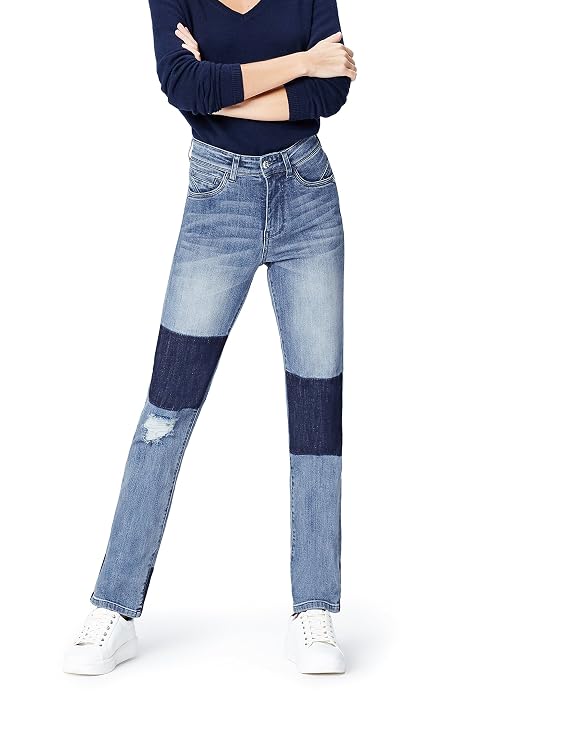 Retrato de cuerpo entero de una persona con jersey azul marino vaqueros patchwork y zapatillas, iluminada con luz natural sobre fondo blanco